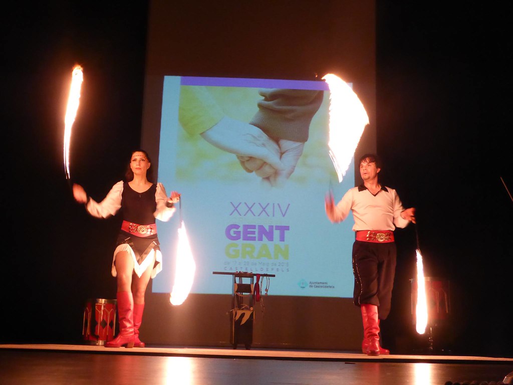 Espectáculo de cuerdas de fuego de Milton y Gala en Castelldefels con el logotipo de la XXXIV Gent Gran proyectado en la pantalla trasera del auditorio.