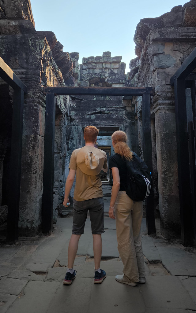 Primer plano de unas zapatillas de senderismo sobre el suelo de piedra antiguo de un templo en Angkor Wat.